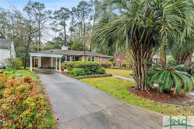 view of front of property featuring a front yard, a carport, driveway, and a chimney