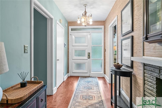 foyer featuring a notable chandelier, baseboards, and light wood-type flooring