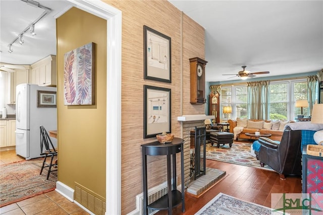 corridor featuring light wood-type flooring, visible vents, baseboards, and track lighting