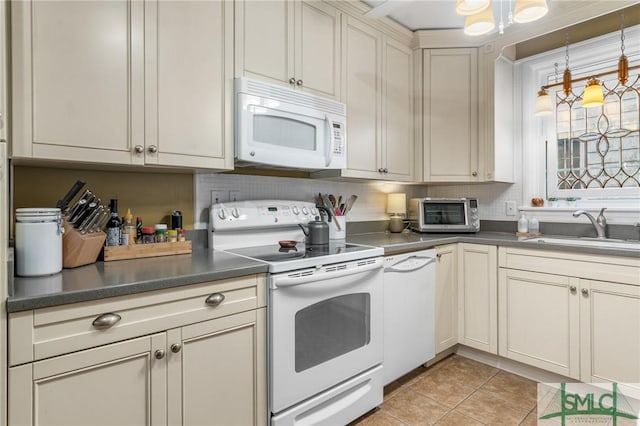 kitchen featuring a sink, dark countertops, white appliances, a toaster, and light tile patterned floors