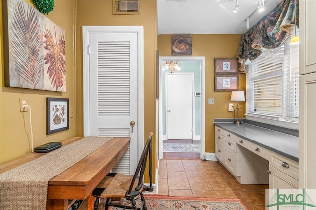 kitchen with visible vents, dark countertops, white cabinets, rail lighting, and light tile patterned floors