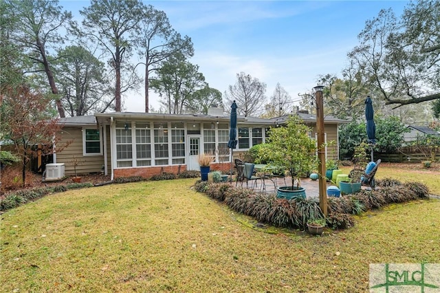 back of house featuring central AC unit, a chimney, a yard, a sunroom, and a patio area