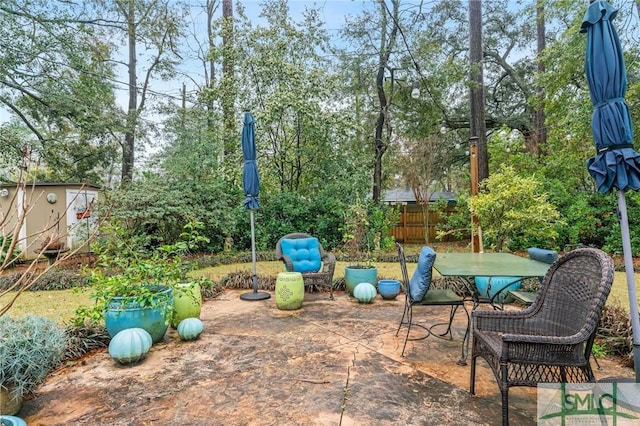 view of patio featuring an outbuilding, outdoor dining space, a storage shed, and fence