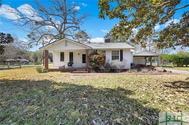 view of front of house with a chimney, covered porch, and a front yard