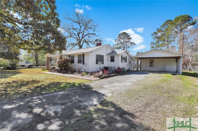 view of front facade featuring a front lawn, driveway, and a chimney