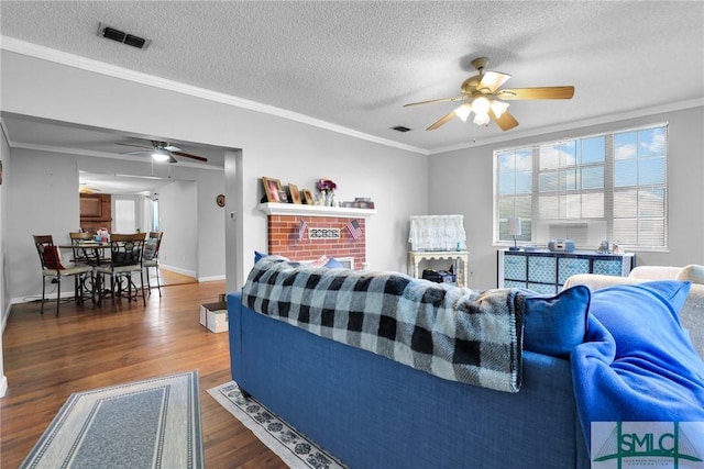 living room featuring visible vents, crown molding, and wood finished floors