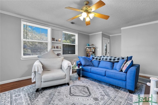 living room with wood finished floors, baseboards, visible vents, a textured ceiling, and crown molding