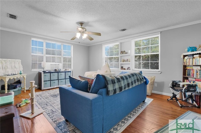 living area featuring hardwood / wood-style floors, crown molding, and visible vents