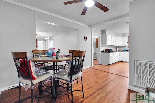 dining space with visible vents, light wood-style flooring, crown molding, and baseboards