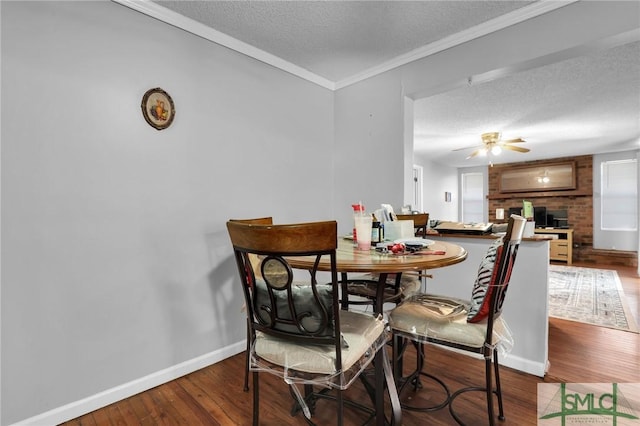 dining area featuring a ceiling fan, wood finished floors, baseboards, ornamental molding, and a textured ceiling