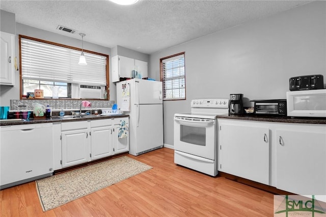 kitchen featuring dark countertops, visible vents, white cabinets, and white appliances