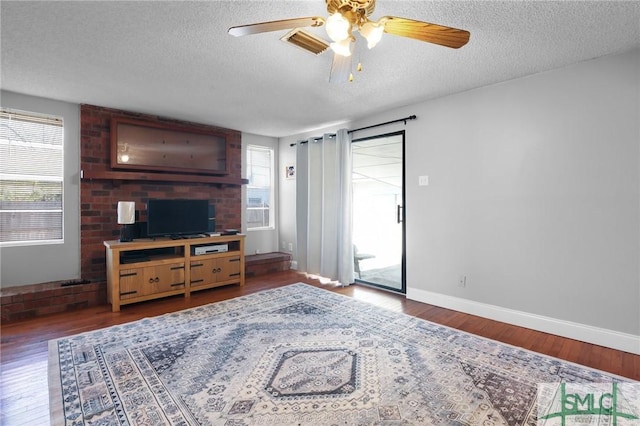 living room with a wealth of natural light, a textured ceiling, and wood finished floors