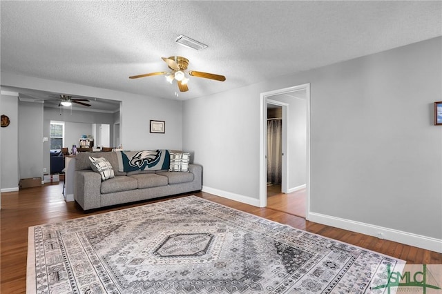 living area featuring visible vents, baseboards, a textured ceiling, and wood finished floors