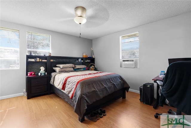 bedroom featuring cooling unit, a textured ceiling, and light wood-style flooring