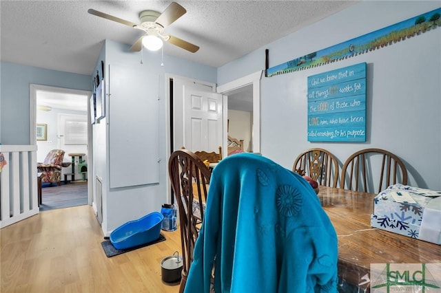 dining space with a textured ceiling, ceiling fan, and wood finished floors