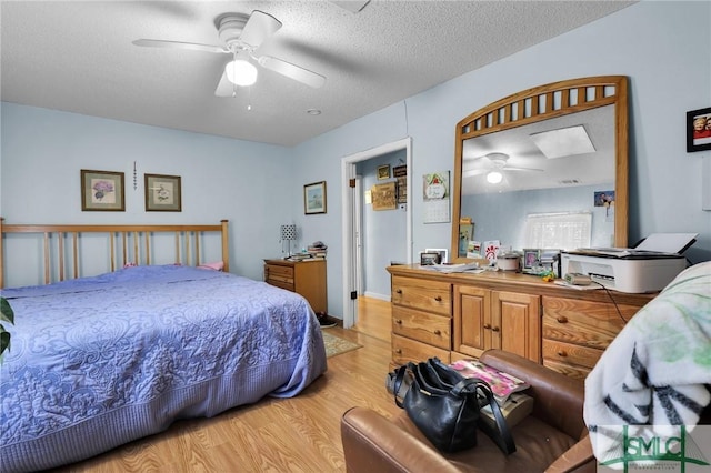 bedroom with ceiling fan, light wood-type flooring, and a textured ceiling