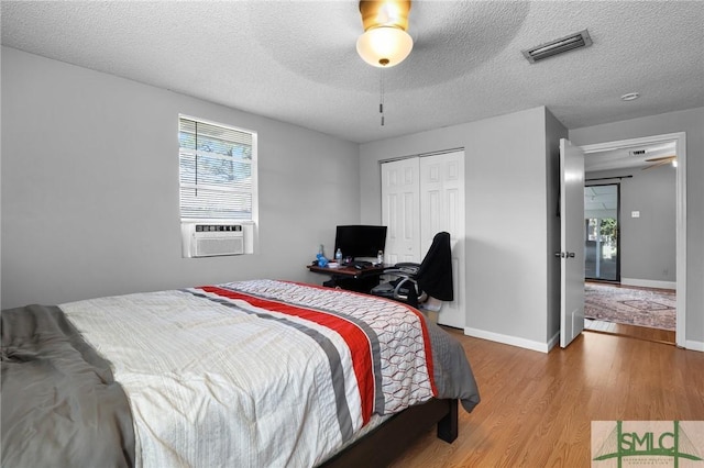 bedroom featuring visible vents, wood finished floors, cooling unit, a closet, and baseboards