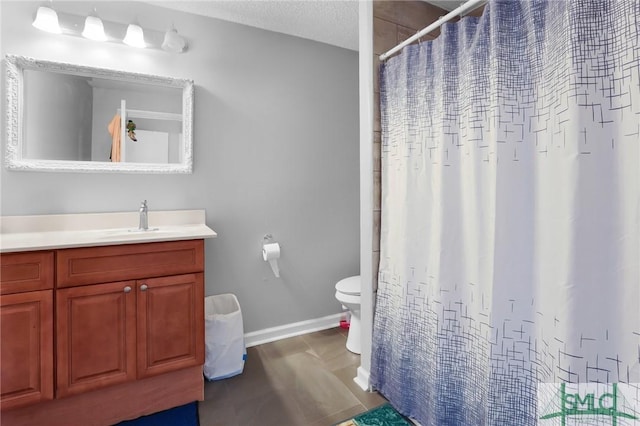 bathroom featuring toilet, a textured ceiling, a shower with shower curtain, baseboards, and vanity