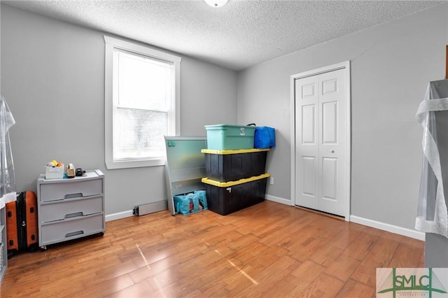 interior space featuring wood finished floors, baseboards, and a textured ceiling