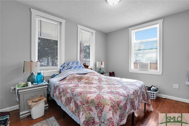 bedroom featuring multiple windows, wood finished floors, baseboards, and a textured ceiling