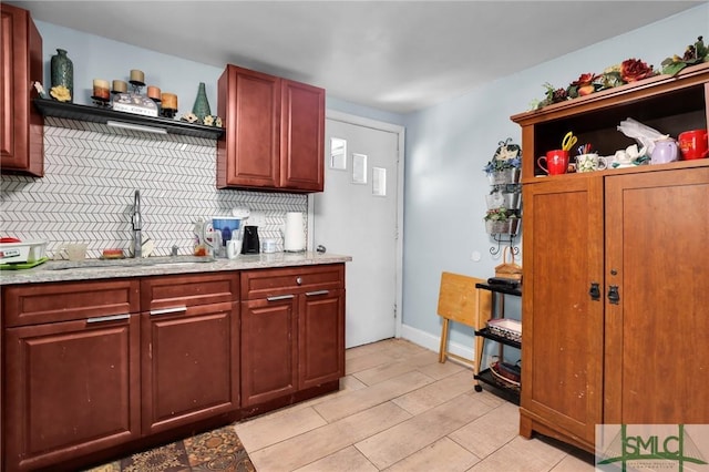 kitchen with tasteful backsplash, light wood finished floors, open shelves, light stone counters, and a sink