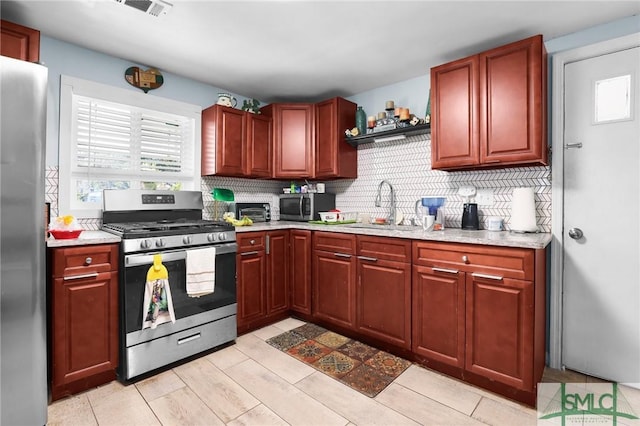 kitchen featuring decorative backsplash, appliances with stainless steel finishes, reddish brown cabinets, and a sink