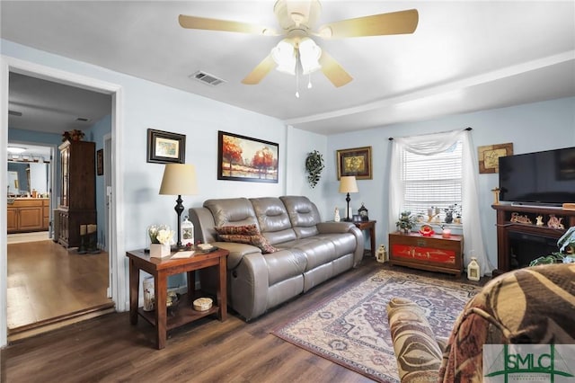 living area with visible vents, a fireplace, a ceiling fan, and wood finished floors