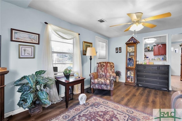 living area featuring visible vents, baseboards, dark wood-type flooring, and ceiling fan