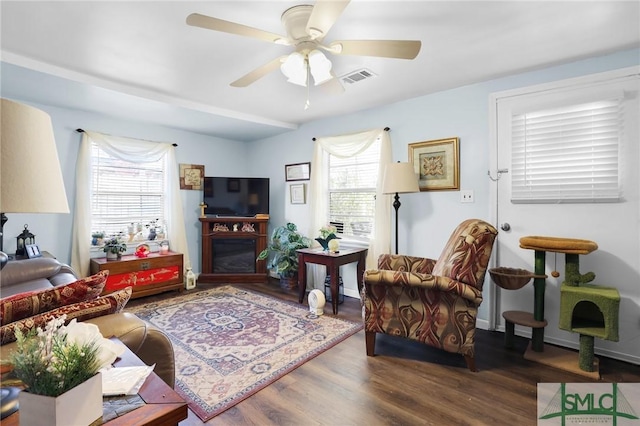 living area with a ceiling fan, wood finished floors, visible vents, and baseboards