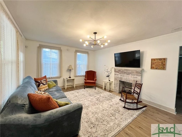 living area featuring a chandelier, baseboards, a brick fireplace, and wood finished floors