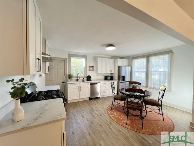 kitchen featuring light wood finished floors, a sink, black appliances, white cabinets, and under cabinet range hood