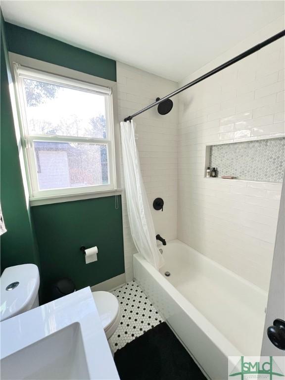 full bath featuring a sink, shower / bath combo with shower curtain, and toilet