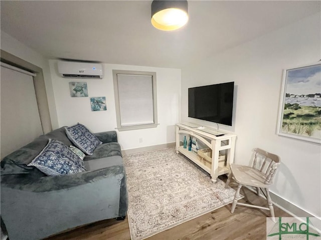 living area with baseboards, wood finished floors, and a wall mounted AC