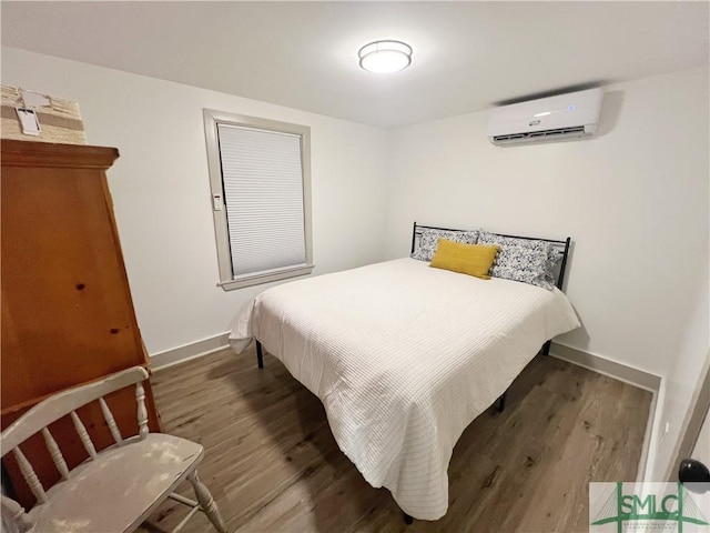 bedroom with a wall mounted air conditioner, baseboards, and wood finished floors