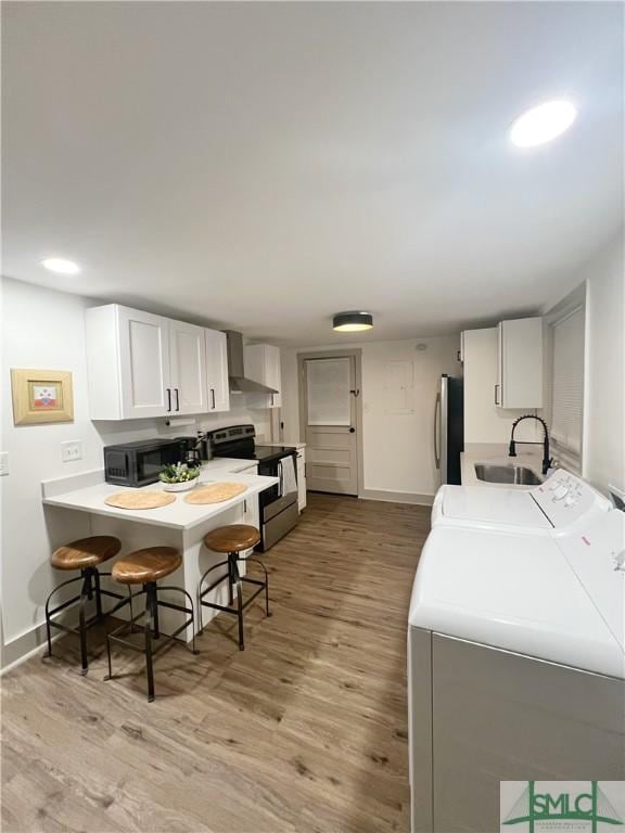 laundry room with washing machine and dryer, light wood-style flooring, baseboards, and a sink