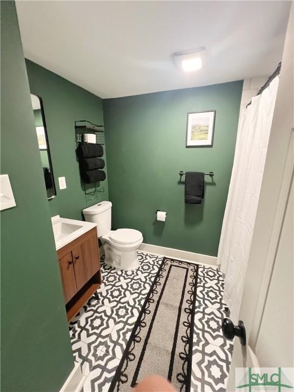 bathroom with baseboards, toilet, and vanity