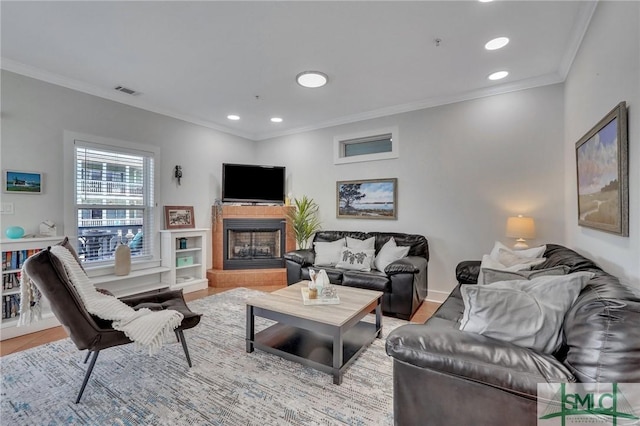 living room featuring recessed lighting, a fireplace with raised hearth, visible vents, and ornamental molding