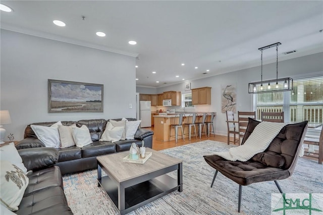 living room with recessed lighting, visible vents, light wood-style floors, and ornamental molding