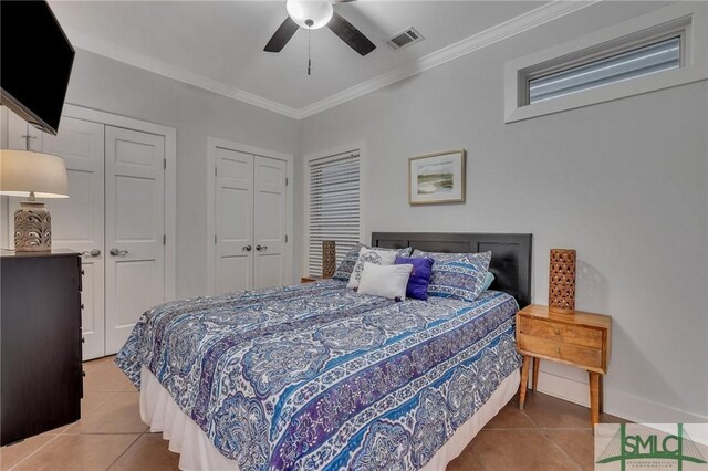 bedroom with light tile patterned floors, visible vents, two closets, and crown molding