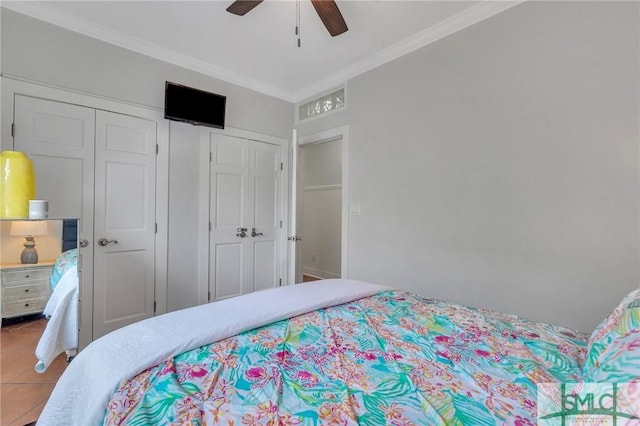 bedroom with tile patterned floors, a closet, ornamental molding, and a ceiling fan