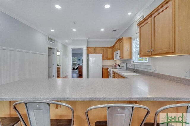 kitchen with light countertops, ornamental molding, white appliances, built in study area, and a sink