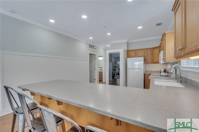 kitchen featuring white appliances, visible vents, a peninsula, a sink, and built in desk