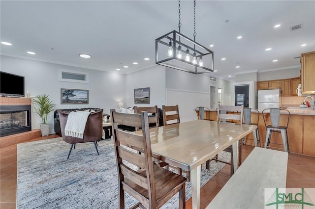 dining room featuring light tile patterned floors, a fireplace with raised hearth, recessed lighting, and ornamental molding