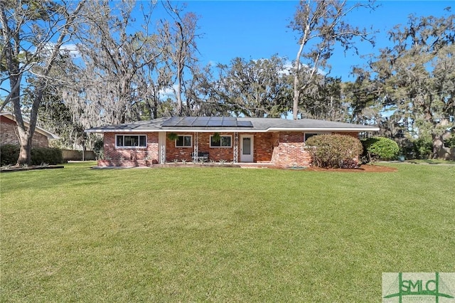 view of front of property with a front lawn, brick siding, and roof mounted solar panels