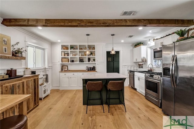 kitchen with visible vents, beam ceiling, open shelves, stainless steel appliances, and a center island