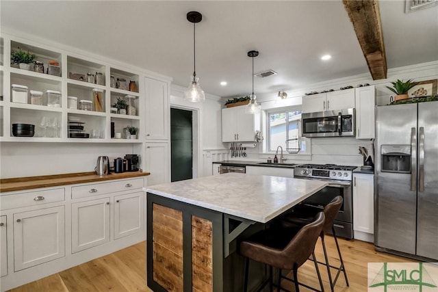 kitchen featuring open shelves, white cabinets, light wood-style flooring, and stainless steel appliances