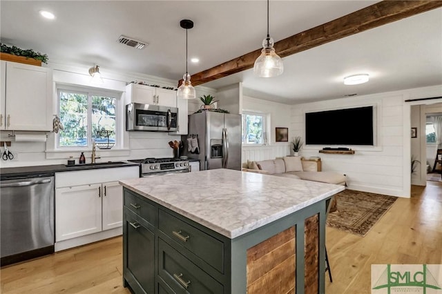 kitchen with visible vents, beamed ceiling, stainless steel appliances, light wood-style floors, and white cabinetry