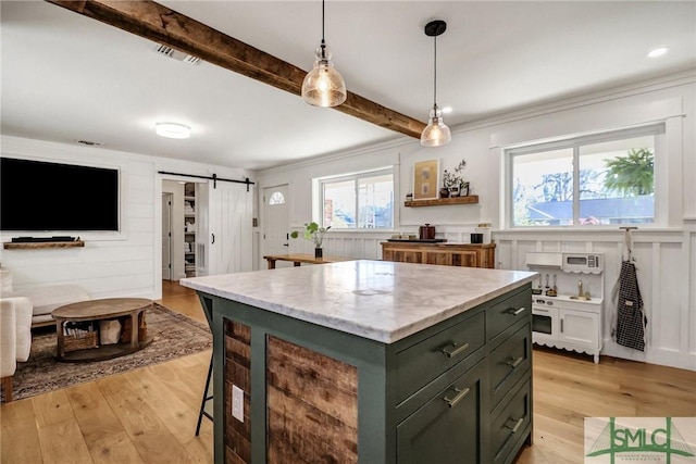 kitchen featuring a barn door, light wood-style floors, beamed ceiling, and visible vents