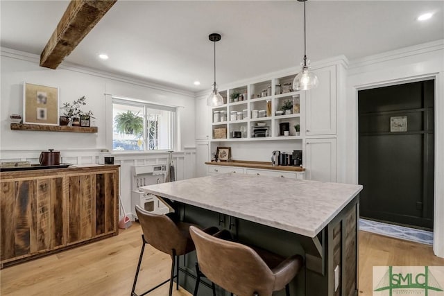 kitchen with white cabinets, pendant lighting, a center island, and light wood-style flooring