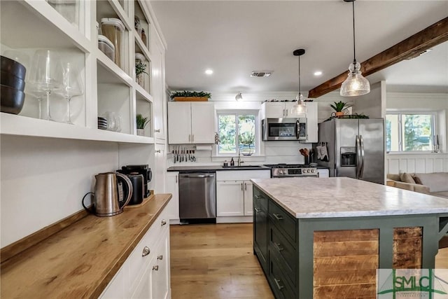 kitchen with light wood finished floors, visible vents, decorative light fixtures, white cabinets, and stainless steel appliances